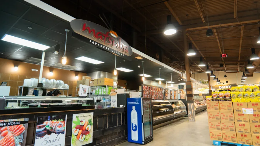 The prepared foods counter at Woo-Ri Mart, under its lit sign