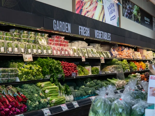 The Garden Fresh Vegetables case at Woo-Ri Mart, stocked with greens, radishes and peppers under English signage